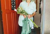 elderly woman at door receiving flowers and bags
